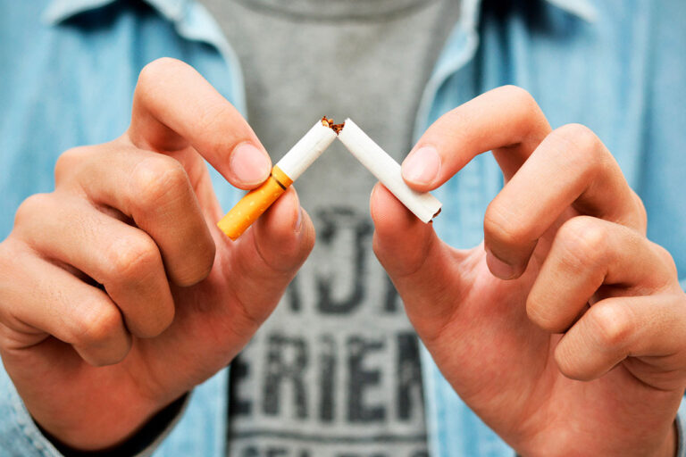 Pessoa quebrando cigarro no meio para parar de fumar