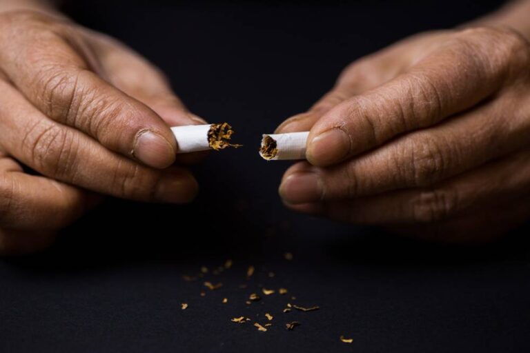 Fumante quebrando cigarro ao meio ao parar de fumar