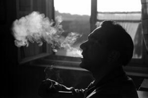 homem fumando na janela