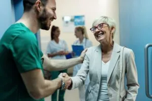 medico dando aperto de mão em mulher idosa