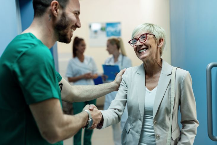 medico dando aperto de mão em mulher idosa