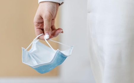 Mão segurando uma máscara facial usada durante a pandemia de coronavírus
