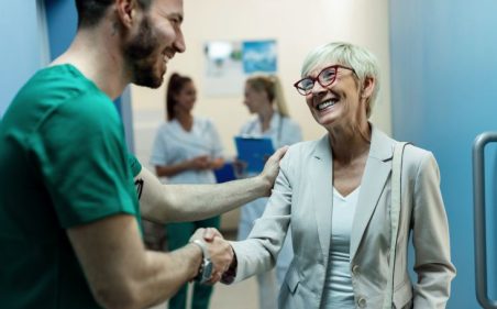 medico dando aperto de mão em mulher idosa